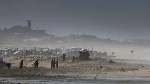 فلسطينيون يتجمعون قرب خيام تأوي نازحين، وسط عاصفة هوائية، في مدينة غزة