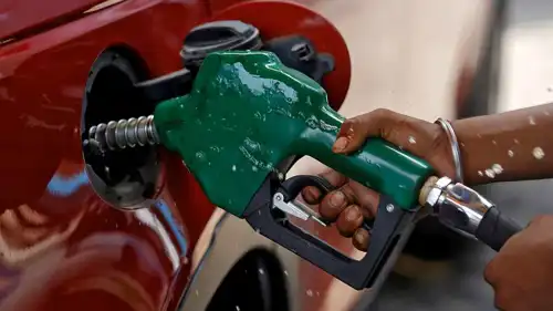 عامل يحمل مضخة وقود لضخ البنزين في سيارة بمحطة وقود.