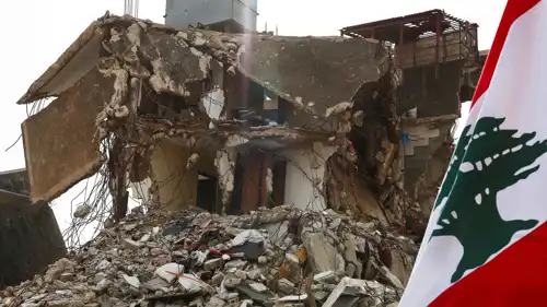 علم لبنان بجوار مبنى متضرر