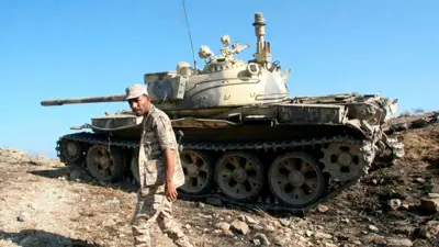 جندي موال للحكومة يمشي أمام دبابة في اليمن