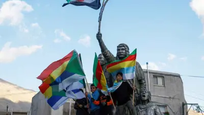 أطفال يحملون أعلام الموحدين الدروز قرب تمثال لسلطان باشا الأطرش