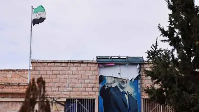 العلم السوري الجديد وملصق ممزق لبشار الأسد في درعا