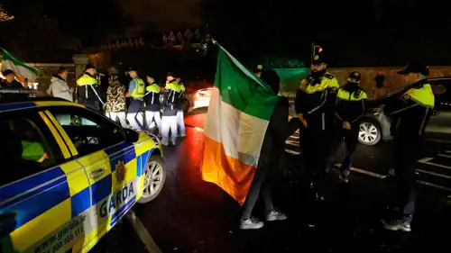 محتج يحمل علم أيرلندا يقف أمام الشرطة