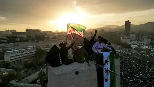 شباب يلوحون بعلم سوريا خلال الاحتفالات في دمشق 