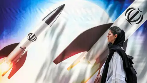 امرأة تمر أمام لافتة تصور إطلاق صواريخ في إيران