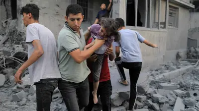 فلسطيني يخلي طفلة من تحت أنقاض مبنى دمرته إسرائيل في غزة