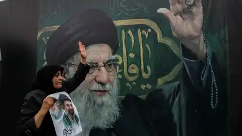 امرأة تحمل صورة مجتبى أمام لافتة عملاقة لعلي خامنئي