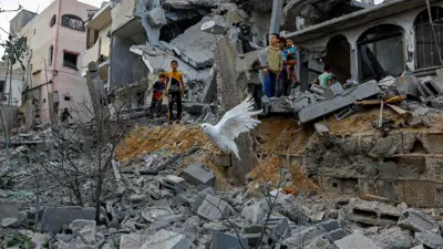 أطفال يقفون على الأنقاض في غزة