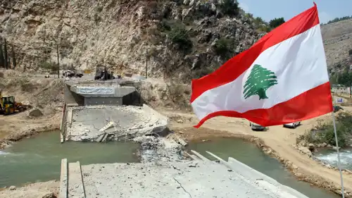 علم لبنان قرب جسر مدمر فوق نهر الليطاني