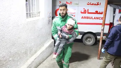 مسعف يحمل طفلاً مصاباً جراء غارة إسرائيلية على غزة
