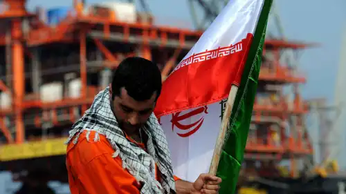 عامل يرفع علم إيران في منشأة نفطية