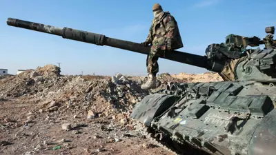 مقاتل من الفصائل المسلحة يعتلي مدفع دبابة للجيش