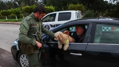 رجل أمن سوري يداعب كلبا عند نقطة تفتيش