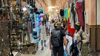 أشخاص يتجولون أمام متاجر الهدايا التذكارية في مراكش