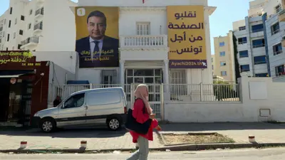 امرأة تمر أمام مقر انتخابي للمرشح العياشي الزمال في تونس