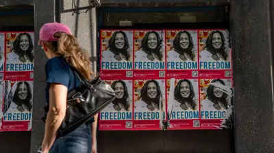 امرأة تمر أمام ملصقات انتخابية لهاريس