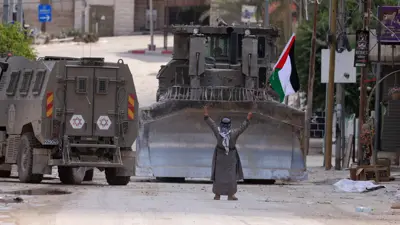 مسن فلسطيني أمام آليات عسكرية إسرائيلية في الضفة الغربية