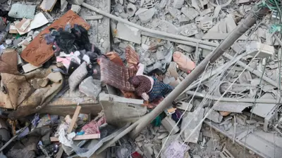 فلسطينية تسير فوق الركام بعد الغارت الإسرائيلية على قطاع غزة