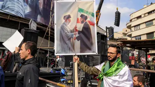 إيراني يحمل صورة مجتبى ووالده علي خامنئي