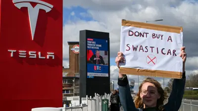 متظاهر يحمل ملصقًا مناهضًا لشركة تسلا
