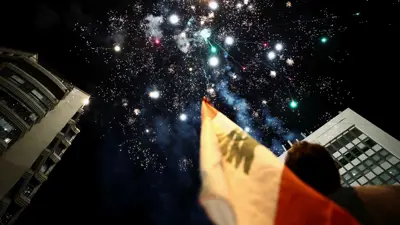 رجل يحمل العلم اللبناني ينظر إلى الألعاب النارية