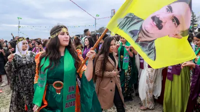 امرأة تحمل علمًا يصور عبد الله أوجلان