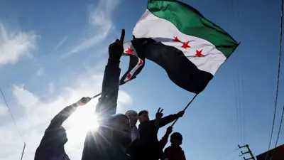 أشخاص يرفعون علم سوريا