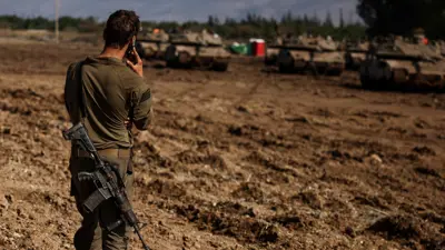 جندي إسرائيلي يقف بالقرب من مركبات عسكرية