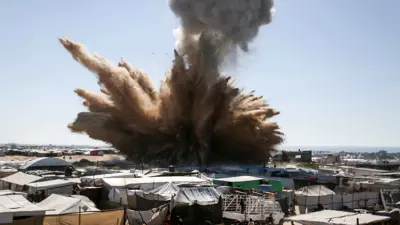 دخان يتصاعد فوق الخيام في مخيم للنازحين الفلسطينيين في شمال خان يونس في جنوب قطاع غزة، أثناء غارة إسرائيلية