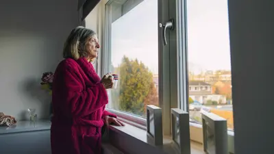 مسنة تقف على النافذة