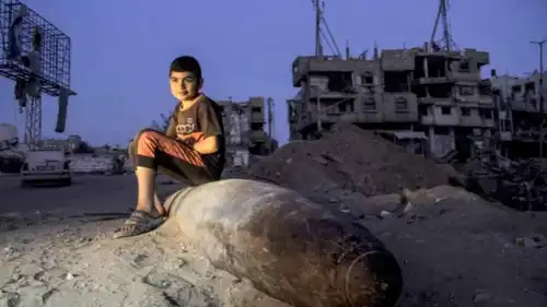 طفل فلسطيني يجلس على مقذوف إسرائيلي لم ينفجر في غزة