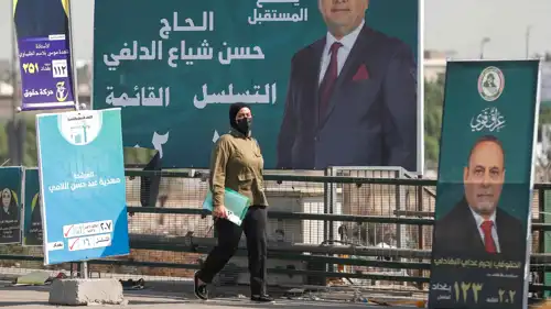 امرأة تمر أمام ملصقات انتخابية في مدينة الصدر العراقية