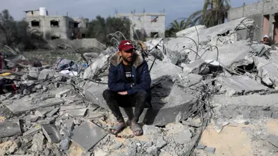 رجل يجلس وسط الأنقاض عقب غارة على منزل في خان يونس