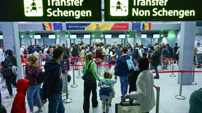 مسافرون يسيرون بجوار لافتات مثبتة تشير إلى مناطق شنغن