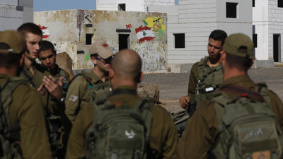 قوات من الجيش الإسرائيلي خلفها شعار لميليشيا حزب الله