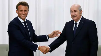 إيمانويل ماكرون مصافحًا عبد المجيد تبون خلال لقاء سابق