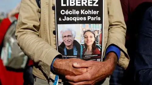 رجل يحمل لافتة عليها صور سيسيل كولر وجاك باريس