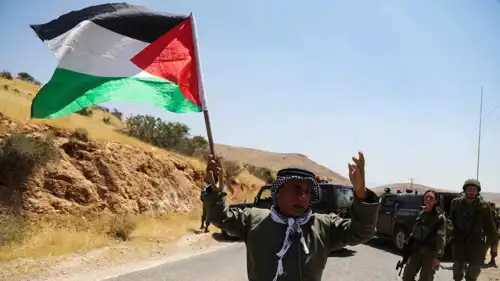 مسن يرفع العلم الفلسطيني أمام قوة إسرائيلية بالضفة