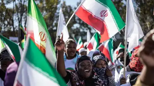 متظاهرون يلوحون بالأعلام الإيرانية أثناء تجمعهم أمام القنصلية الأمريكي