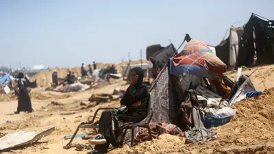 امرأة في مخيم خان يونس تنظر إلى الخراب