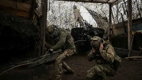 جنديان أوكرانيان يطلقان قذيفة هاوتزر