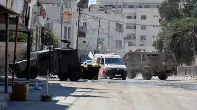 سيارة إسعاف تسير بين مركبات عسكرية إسرائيلية تشارك في مداهمة في جنين بالضفة الغربية