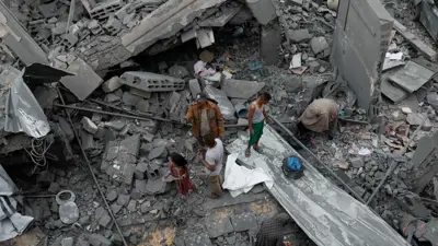 فلسطينيون يتفقدون موقع غارة إسرائيلية على منزل في غزة