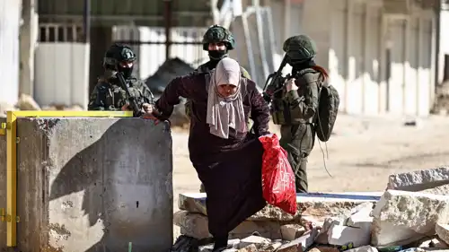 سيدة فلسطينية تسير بجانب عناصر من الجيش الإسرائيلية