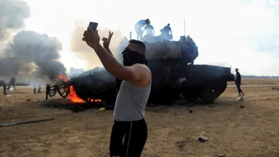 فلسطينيون قرب دبابة إسرائيلية محترقة في 7 أكتوبر 2023