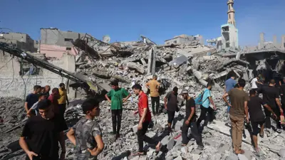 فلسطينيون يتفقدون موقع غارة إسرائيلية على مخيم البريج للاجئين الفلسطينيين في وسط قطاع غزة