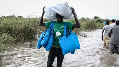 رجل من جنوب السودان يحمل أمتعته أثناء سيره في منطقة غمرتها الفيضانات، ولاية بوما، شرق جنوب السودان