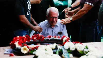 رجل يتفاعل مع حضور أقاربه وأصدقائه جنازة قتلى الخطيب خلال هجوم صاروخي من إيران على طمرة، شمال إسرائيل