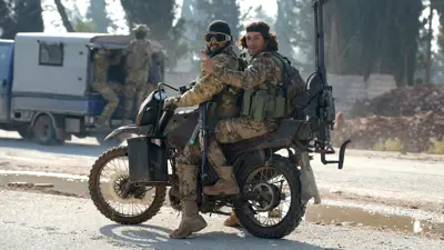 عنصران من الفصائل المسلحة يحتفلان بالسيطرة على حلب