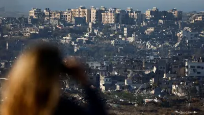 امرأة إسرائيلية تنظر إلى شمال غزة باستخدام منظار